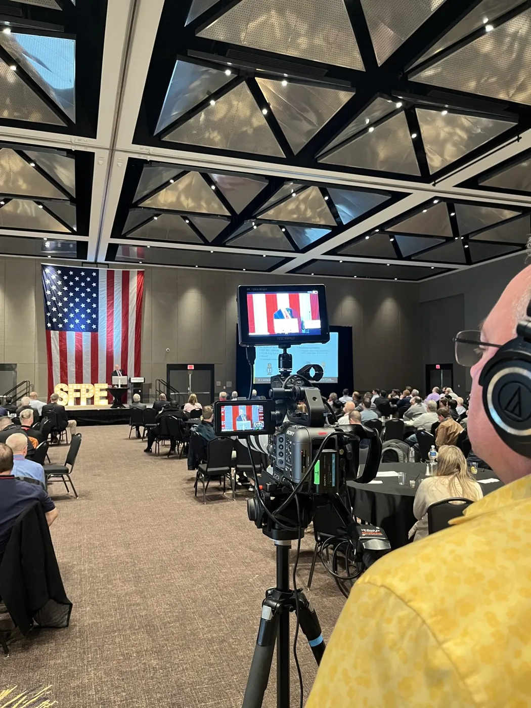 Camera operator recording a corporate event for an audience at an on-location venue