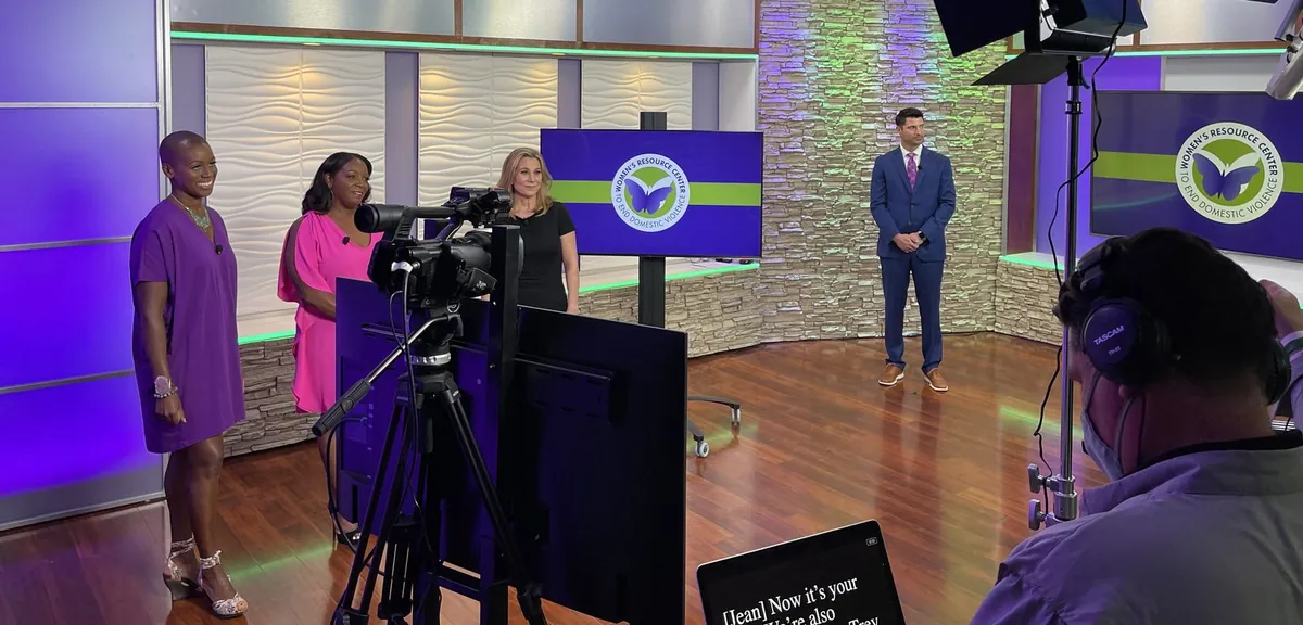 Multi-camera corporate video production with presenters, studio cameras, lighting, and a branded video wall