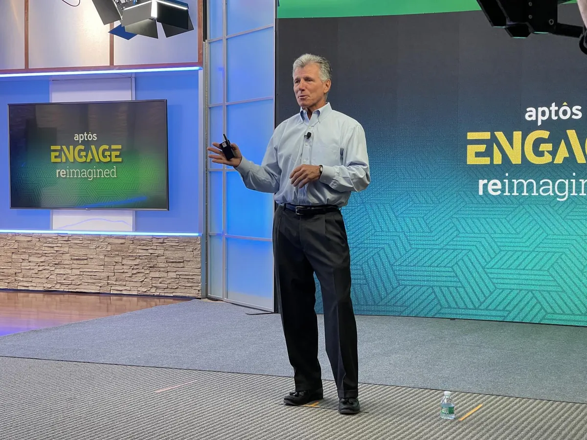 Corporate presenter recording an educational presentation beside branded display screens