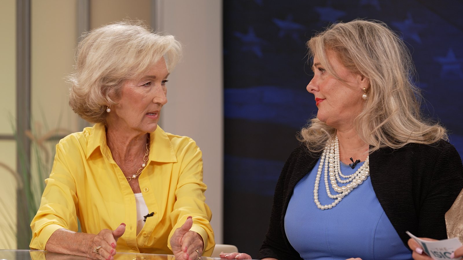 Two presenters in a professionally lit studio discussion for a recorded communications program