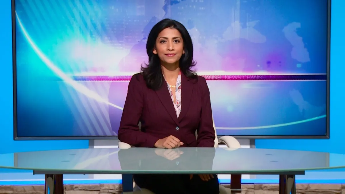 Executive presenter delivering a direct-to-camera message from a professional news desk set