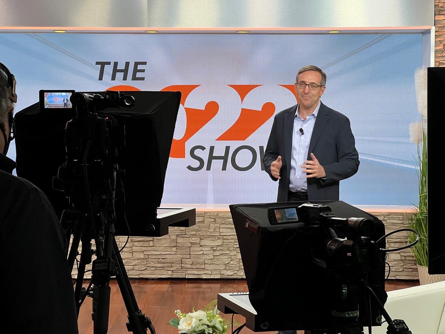 Studio cameras and teleprompter framing an executive presenter during a corporate video production